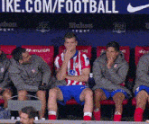 a group of soccer players are sitting in a row in front of a nike sign
