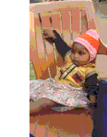 a baby girl wearing a knitted hat is sitting on a chair .