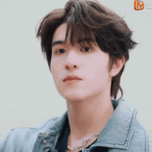 a young man wearing a denim jacket and a necklace