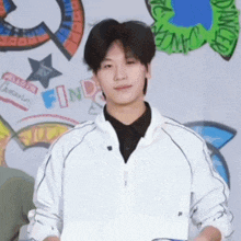 a young man in a white jacket stands in front of a sign that says find