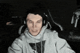 a man wearing headphones and a white hoodie is looking at the camera