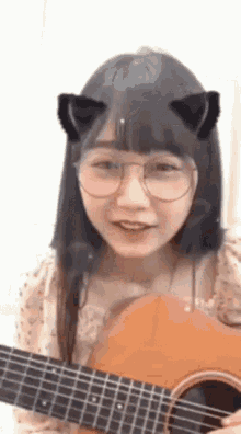 a girl with cat ears is playing a guitar .