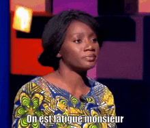 a woman in a colorful shirt is talking into a microphone and says on est fatigue monsieur