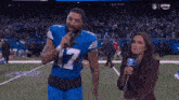 a football player is singing into a microphone while a woman holds a microphone