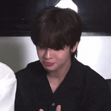 a young man in a black shirt is crying while sitting in front of a tv .