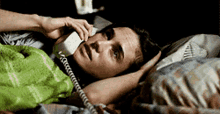 a man is laying in bed talking on a telephone
