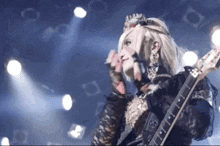 a woman with a crown on her head is holding a guitar .