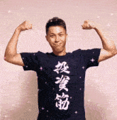 a man in a black shirt with chinese writing on it flexes his arms