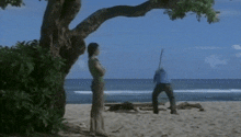 a man and a woman standing on a beach looking at the ocean