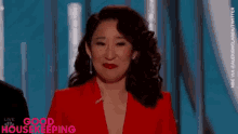 a woman in a red jacket and red lipstick is standing in front of a blue background .