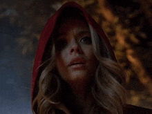 a woman is wearing a red hood and looking at the camera