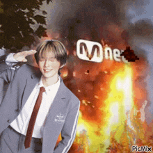 a man in a suit and tie saluting in front of a mnet logo