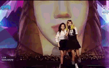 two girls singing in front of a giant face that says sb on the bottom