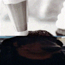 a close up of a person 's face with a cup of coffee behind them