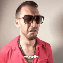 a man wearing sunglasses and a red shirt has the word modh on the bottom