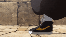 a person wearing a pair of black shoes with a yellow swoosh on the side