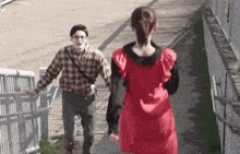 a man and a woman are walking down stairs . the woman is wearing a red dress .