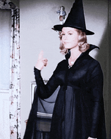 a woman in a black witch costume giving a thumbs up