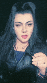 a woman in a leather jacket is holding a pair of earbuds