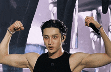 a man flexes his muscles in front of a microphone with the letter f on his chest