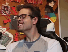 a man wearing glasses is smiling in front of a bulletin board that says " canned "
