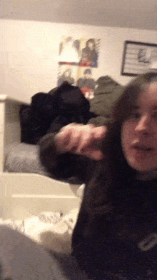 a girl is brushing her hair in a bedroom with a poster on the wall