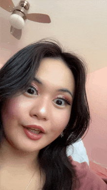 a close up of a woman 's face with a ceiling fan above her head