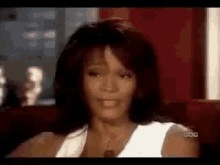 a woman in a white tank top is sitting in a chair .