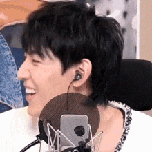a man wearing headphones is sitting in front of a microphone and smiling .