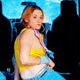 a woman wearing a yellow tank top and blue jeans