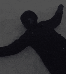 a person wearing a black jacket is laying in the snow