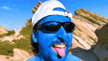 a man with blue paint on his face wearing sunglasses and a hat