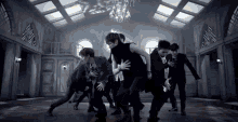 a group of young men are dancing in a dark room with a chandelier .