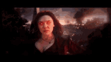 scarlet witch from avengers : age of ultron is standing in the middle of a battle in a red dress .