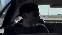 a man wearing a hat and sunglasses is sitting in a car