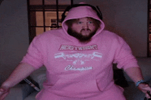 a bearded man wearing a pink hoodie that says heavyweight champion