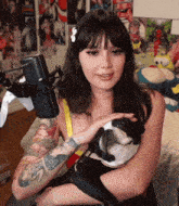 a woman with tattoos is holding a dog in her arms in front of a microphone .