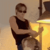 a man wearing sunglasses and headphones is standing next to a lamp in a room .
