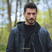 a man with a beard is wearing a black leather jacket and a black sweater