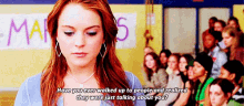 a girl with red hair is standing in front of a crowd of people and talking about them