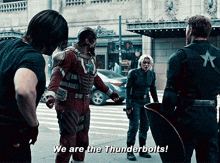 a group of avengers are standing on a sidewalk and one of them is saying we are the thunderbolts