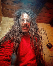 a man with long hair and glasses wearing a red shirt
