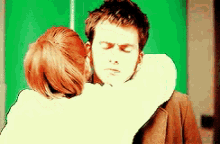 a man and a woman hugging each other with their eyes closed