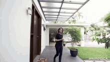 a woman is standing in front of a house with the words made in animatica on the bottom