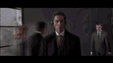a man in a suit and tie is wearing headphones while another man stands behind him