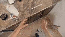 a person 's hands are reaching into a drawer in a messy room