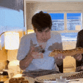 a man in a blue shirt is eating a large slice of pizza
