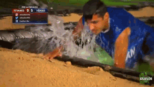 a man in a blue shirt is crawling through a pool of water