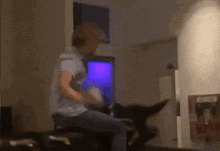 a man is sitting on a couch in a living room and talking on a cell phone .