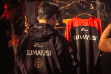 a man wearing a black jacket that says gumayusi on the back